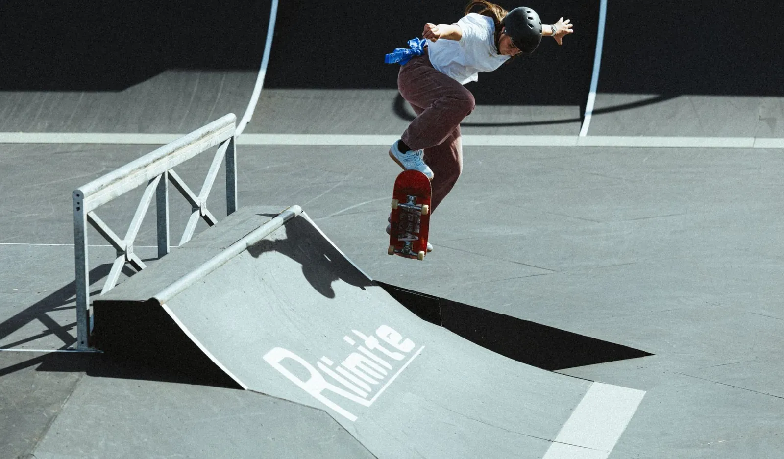 Skateuse en plein saut au-dessus d'un module de skatepark